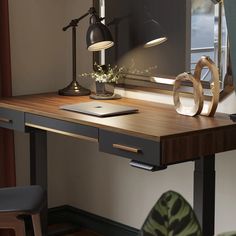 a desk with a lamp, mirror and laptop on it in front of a window