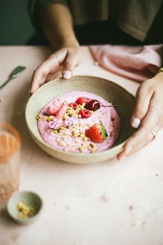 a person holding a bowl of food on top of a table with utensils