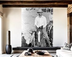 a black and white photo of a man on a horse in a living room with couches