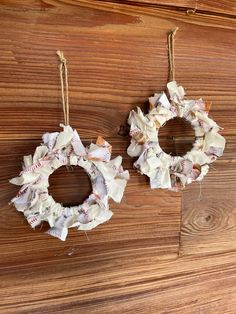 two small wreaths hanging from strings on a wooden surface