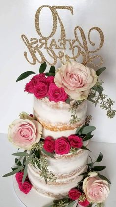 a three tiered cake with pink flowers and greenery on top, next to the word 70th birthday written in gold