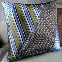 a blue and green striped pillow sitting on top of a wooden bench next to a wall