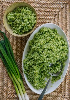 two bowls filled with green food on top of a woven place mat next to onions