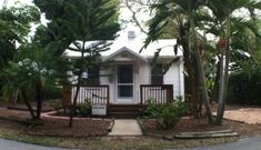 a small white house surrounded by trees and bushes