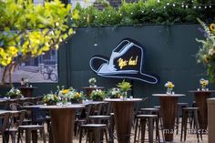 an outdoor dining area with tables and chairs set up in front of a large sign