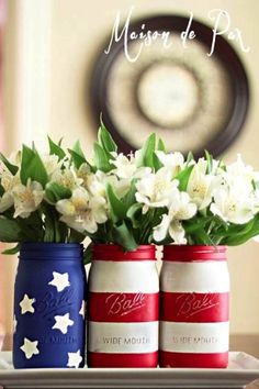 three red, white and blue mason jars with flowers in them sitting on a tray