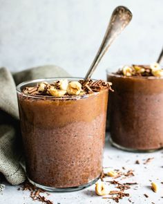 two glasses filled with chocolate pudding and topped with nuts