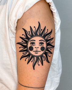 a sun tattoo on the right arm and shoulder, with an evil face in the center