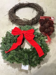 two wreaths with red bows are sitting on the floor next to each other,