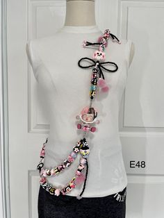 a mannequin wearing a white top with pink and black beads on it's neck