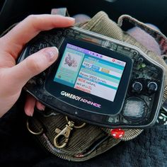 a person is holding a gameboy advance in their hand while sitting in a car