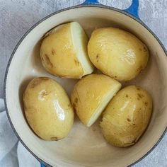 four potatoes in a bowl on a blue and white cloth