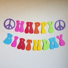 a happy birthday banner with peace signs hanging from it's side on a wall