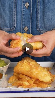 a person holding food in their hands and dipping sauce on the other hand, while another person holds up a piece of food