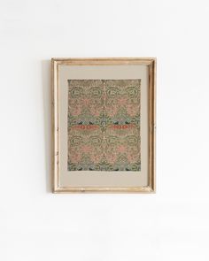 a painting hanging on the wall in front of a white wall with a wooden frame