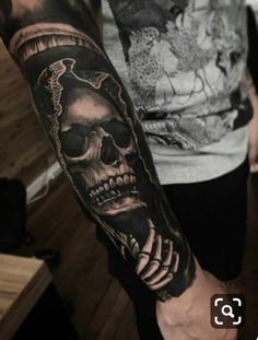 a man's arm with a skull and snake tattoo on the left side of his arm