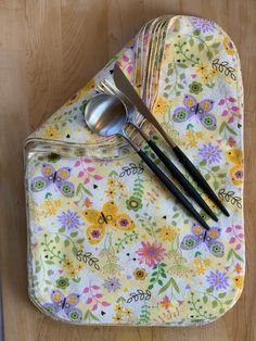 two spoons and fork sitting on top of a flowered cloth covered placemat