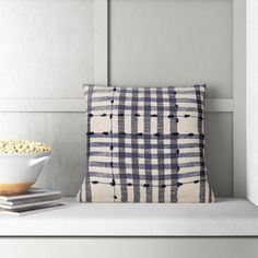 a bowl of popcorn sitting on top of a shelf next to a pillow and book