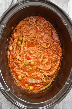 an overhead view of a stew in a crock pot with olives and peppers