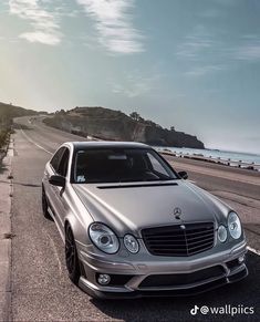 a silver mercedes cls parked on the side of the road next to the ocean