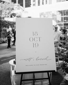 a sign that is sitting in front of a planter with people standing around it