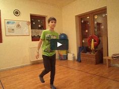 a young man in a green shirt is playing with a frisbee on the floor