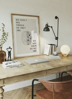 a wooden desk topped with a laptop computer next to a lamp and vase filled with flowers