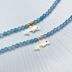 These handcrafted bracelets feature high quality Aquamarine and a hand carved Mother of Pearl dolphin charm with a durable magnetic clasp. Aquamarine is believed to provide hope, peace, and tranquility while dolphins further symbolize harmony and grace. Your purchase will include one Aquamarine Dolphin Bracelet in either Sterling Silver or 14k Gold Filled and Free Shipping. A free re-usable microfiber pouch will be included to ensure safety while shipping your bracelet! MEASUREMENTS The aquamari Ocean-inspired Blue Charm Bracelet For Gifts, Blue Beaded Bracelets With Lobster Clasp For Gift, Dolphin Charm, Bracelet Measurements, Dolphin Bracelet, Blue Dolphin, Red Bank, Blue Charm, Handcrafted Bracelets