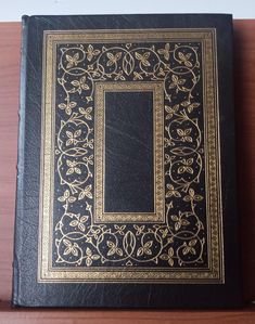 a black and gold book sitting on top of a wooden table