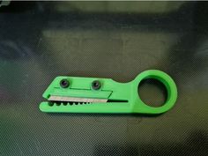 a green pair of scissors on top of a black surface with holes in the middle