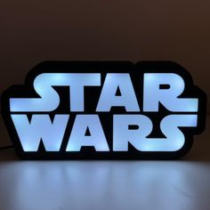 the star wars logo is lit up with blue light and sits on a white surface