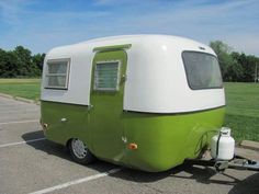 a green and white trailer parked in a parking lot next to a grass covered field