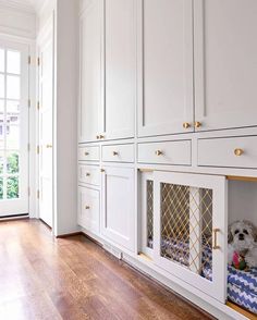 a dog bed in the middle of a room with white cabinets and wood flooring