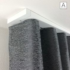 two gray curtains hanging on the side of a wall