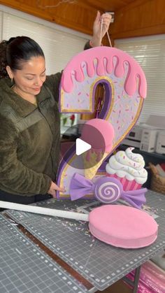 a woman is decorating a cake with pink icing