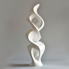 a tall white sculpture sitting on top of a table next to a gray wall and floor