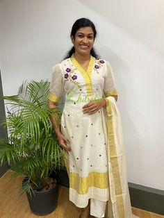 Kakkapoovu- this flower commonly seen in Villages of Kerala, used to make athapoovu in Onam days- Festival of Kerala. The flower motifs made with silk threads and enhance with golden mirrors. Purple resham and golden jerry polka dots are the speciality of the dress. Kasavu collar highlighted with golden potli buttons. The kurti paired with an ivory bottom & dupatta.  OUTFIT : Top, Bottom & Dupatta MATERIAL : Top-Kerala Handloom Cotton & Gold Kasavu Work : Kakkapoovu flower done by resham and jer White Handloom Straight Kurta, Traditional Cotton Silk Kurta With Dori Work, Traditional Cotton Silk Wear With Dori Work, Traditional Kurta With Dori Work, Traditional Cotton Silk Kurta For Puja, Traditional Cotton Wear With Dori Work, Ceremonial Cotton Dupatta With Zari Work, Traditional Salwar Kameez With Dori Work For Puja, Traditional Salwar Kameez With Dori Work