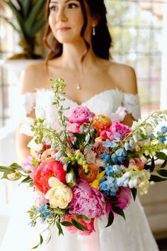 a woman in a wedding dress holding a large bouquet with flowers on it's side