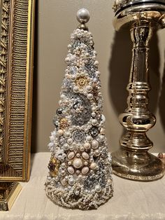 a small christmas tree sitting on top of a table next to a gold framed mirror