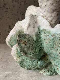 a white and green sculpture sitting on top of a cement floor next to a wall