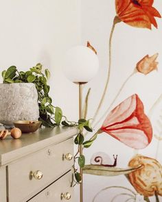 a white dresser topped with a cake next to a flower covered wallpapered wall