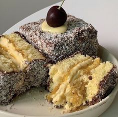 a white plate topped with cake covered in powdered sugar and a cherry on top