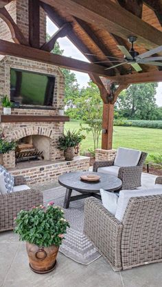 an outdoor living area with wicker furniture and a television on the wall above it