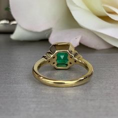 "The ring pictured is lab created emerald with moissanite accents. Also shown in 14k white gold instagram: https://www.instagram.com/p/BvKUII-lfxA/ -Approximate total carat weight: approx. 2.30ctw diamond equivalent -Center Stone Size: 8x8mm - approx. 2.20ct diamond equivalent -Center Stone Shape: asscher -Gem Type: lab created emerald -Stone Clarity: VS2 -Stone Color: Green -Moh's Scale: 8.5 hardness -Side Stones Size: 6 round - approx. 0.12ctw. diamond equivalent -Gem Type: moissanite -Metal T Asscher Cut Emerald Ring With Accent Stones, Heirloom Emerald Ring With Bezel Setting For May Birthstone, Heirloom Emerald Ring With Bezel Setting, Bezel Set Baguette Cut Emerald Ring, Emerald Baguette Cut Ring With Bezel Setting, Emerald Ring With Bezel Setting For Anniversary, May Birthstone, Heirloom Emerald Ring With Accent Stones And Round Cut, Gia Certified Emerald Anniversary Ring, Baguette Cut Emerald Ring With Bezel Setting