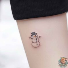 a small snowman tattoo on the left thigh, with a top hat and tail