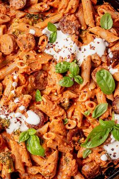 a skillet filled with pasta and meat covered in sauce, cheese and spinach