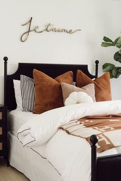 a bed with lots of pillows on top of it next to a wooden sign that says welcome