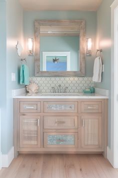 a bathroom with blue walls and wooden cabinets, white counter tops and light wood flooring