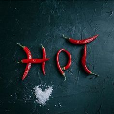 three chili peppers with the word hot spelled out in front of them on a black surface