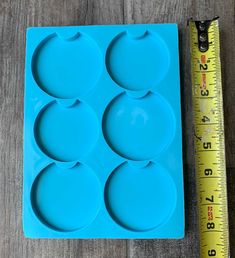 a blue tray with four circles on it next to a measuring tape